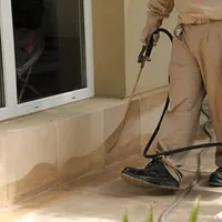 General pest control technician spraying exterior perimeter around a home in Cleveland, OH