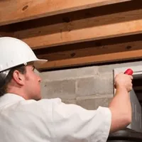 Termite inspection technician checking a basement wall and framing for termite activity in Cleveland, OH